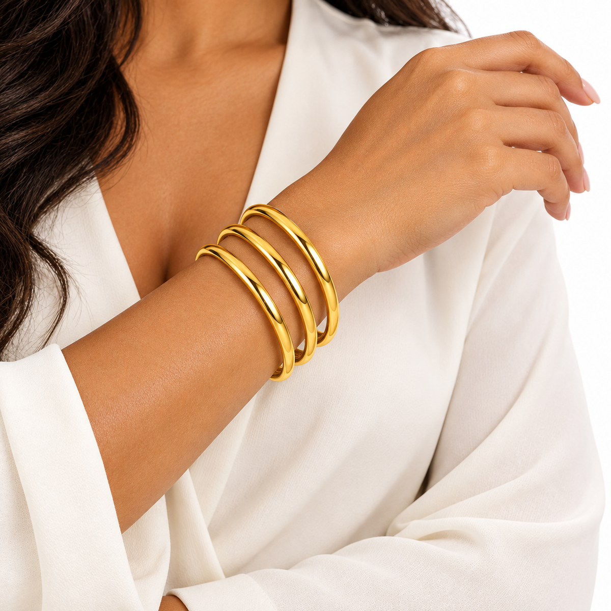 Set de 3 pulseras tipo Bangle doradas con diseño liso y acabado brillante, lucidas en la muñeca de una mujer. bravachic.